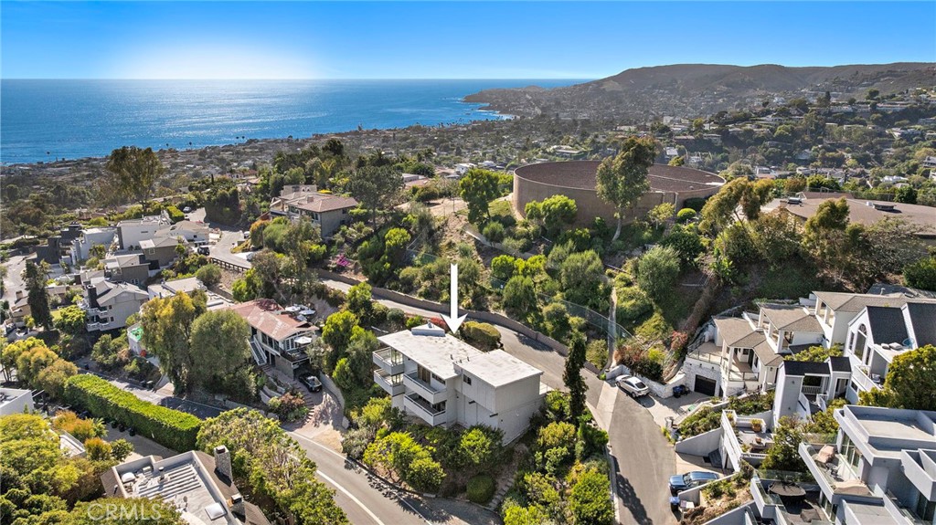 Aerial view over the hillside to the ocean, with an arrow marking the house at 888 Summit Drive, Laguna Beach
